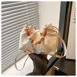 Detail of white pleated bucket bag with amber gradient beaded handle and logo
