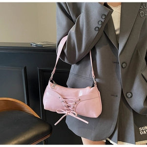 Dettaglio della borsa baguette in vernice rosa con lacci incrociati e fiocco decorativo