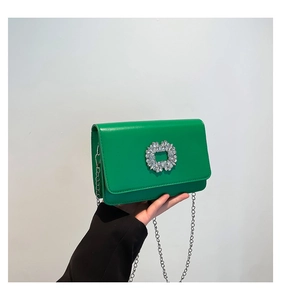 Close-up of vibrant green leather square bag featuring a large sparkling crystal buckle