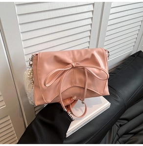 Detail of light pink ballet-style bag with bow, pearl charms and lace detail