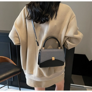 Close-up of minimalist gray fabric and black leather contrast stitching on crossbody bag