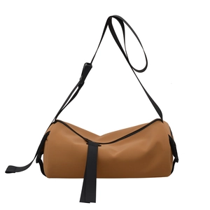 Minimalist camel cylinder crossbody bag with adjustable black nylon strap and matte leather finish