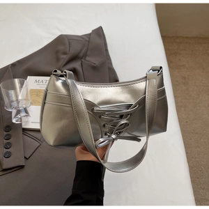 Dettaglio della borsa metallizzata argento con fiocchi decorativi e cerniera scorrevole