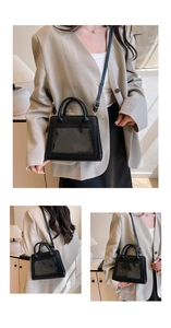 Detail view of black handbag with transparent window and gold hardware on beige blazer