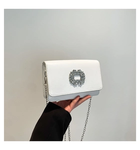 Detail of white mini square bag with crystal flower buckle and silver chain strap