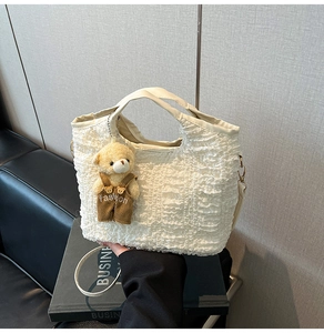 Détail du sac blanc à texture gaufrée avec un pendentif ours mignon sur des livres