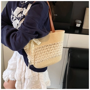 Close-up of beige woven tote bag with lace bow and brown leather handles in lifestyle setting
