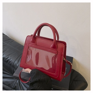 Detail of red leather crossbody bag with a large transparent PVC window and top handle