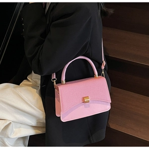 Detail of pink leather handbag with textured flap and gold metal hardware on model