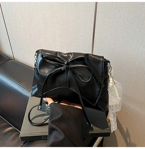 Détail d'un sac noir à nœud avec pendentif en perles et dentelle élégante