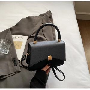 Detail of a minimalist square crossbody bag with textured patchwork and gold magnetic buckle