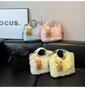 Detailed shot of pleated fabric bucket bags in five colors with cute bear charms