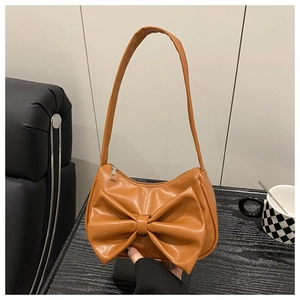 Close-up of caramel PU leather hobo bag featuring a large decorative bow and top zipper
