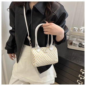 Detail of checkered cylinder bag with silver butterfly buckle and long shoulder strap