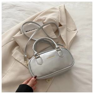 Dettaglio borsa argento in pelle con fibbia dorata su elegante blazer beige
