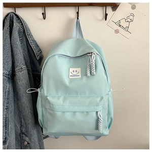 Détail d'un sac à dos en nylon bleu clair avec logo tendance et tirettes de zip tissées