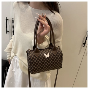 Detail view of brown vintage cylinder bag with monogram pattern and white butterfly detail