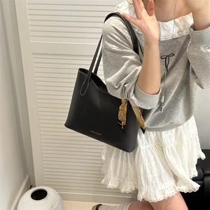 Classic black tote bag with white contrast stitching and a printed scarf accent on the handle