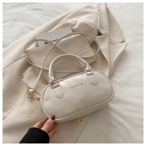 Dettaglio borsa a tracolla beige di lusso con finiture dorate e logo inciso