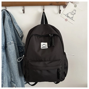 Détail du sac à dos en nylon noir avec logo smiley et tirettes de fermeture tressées