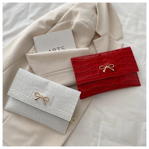 Détail de pochettes en cuir synthétique rouge et blanc à motif pierre et boucle nœud doré