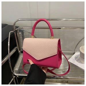 Detail of pink leather small crossbody bag featuring beige woven texture flap and gold hardware