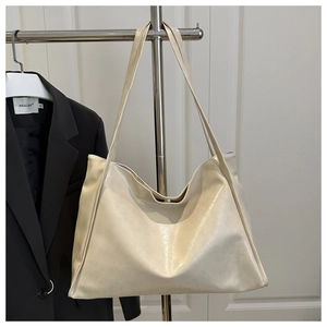 Détail d'un grand sac cabas crème avec finition brillante et deux fines bandoulières