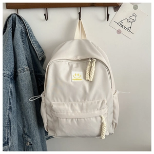 Détail du sac à dos en nylon blanc cassé avec écusson smiley et fermetures éclair tissées