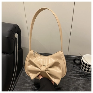 Close-up of beige shoulder bag featuring a large bow detail and soft faux leather texture
