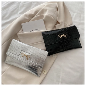Détail du sac enveloppe avec texture pierre et boucle en métal doré en forme de nœud
