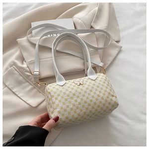Detail of white and yellow Boston bag with gold butterfly accent on cream blazer