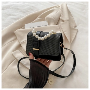 Detail of black woven PU leather bag featuring elegant white pearl handle and shoulder strap