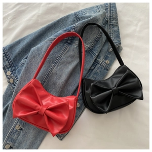 Flat lay of red and black shoulder bags with large bow details on denim jacket