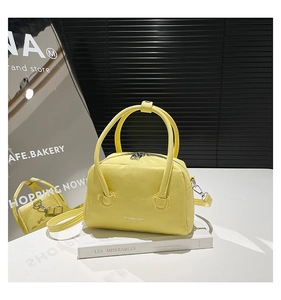 Detail of yellow lychee texture boston bag featuring silver zipper and sturdy metal feet