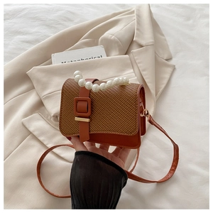 Detail of woven brown PU leather bag with elegant pearl handle and vintage clasp