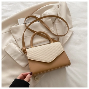 Detail of elegant two-tone crossbody bag with woven flap and smooth brown texture