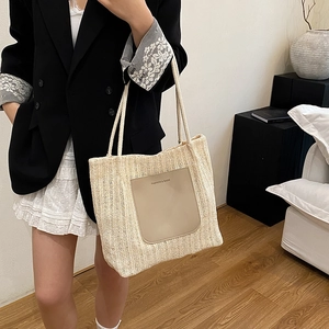 Beige woven straw tote bag with brown leather pocket and rope handles for beach vacation