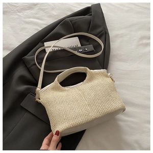 Close-up of woven straw bag detail with cream leather handles and gold metal hardware