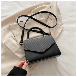 Detail view of the gray woven texture stitching on the black leather flap of the handbag