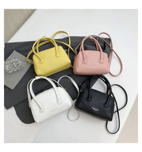 Flat lay of colorful Boston bags in yellow, pink, white, and black with textured leather