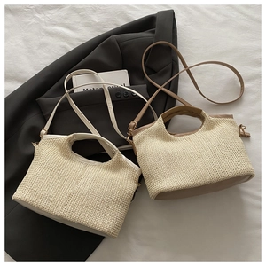 Detail of woven straw tote bag with synthetic leather handle and adjustable strap