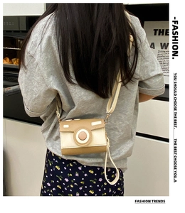 Fashionable camera-shaped crossbody bag worn by a woman in a minimalist modern setting