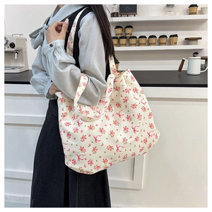 Detail of floral canvas tote bag showing the pink flower pattern and bow on a shoulder bag