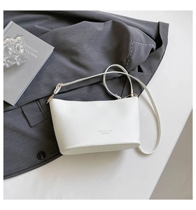 Detail view of the white pebble leather bucket bag featuring gold-tone hardware buckles
