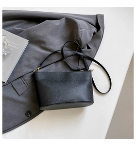 Close-up of black litchi grain leather bucket bag with elegant gold-tone hardware detail