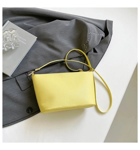Close-up of bright yellow lychee texture leather bucket bag with gold metal buckle