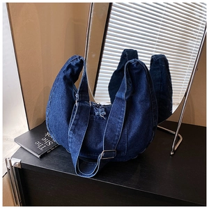 Detail view of deep blue denim crescent hobo bag with adjustable strap and metal buckle