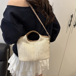 Handwoven straw tote bag in beige with brown leather straps shown on model back