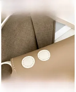 Detail view of the brown faux leather bag with white circular stitching and strap