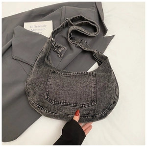 Detail of dark grey denim crossbody bag featuring external front pockets and adjustable strap